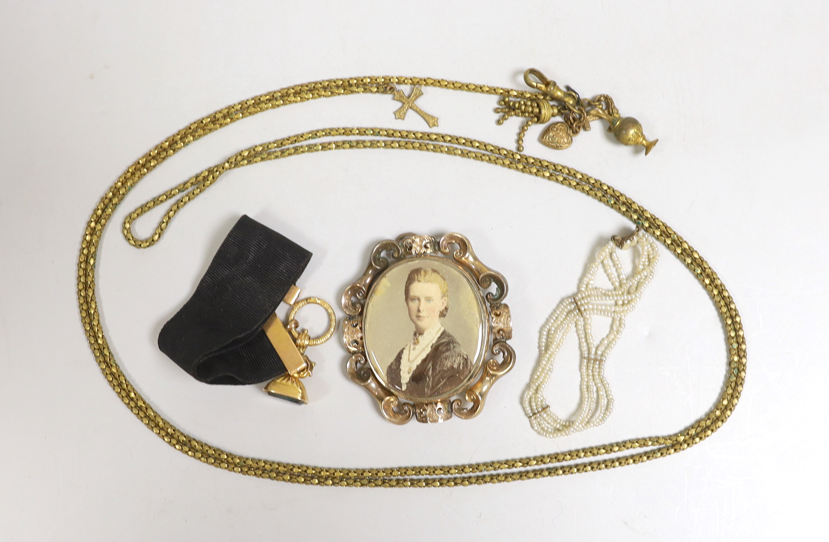 A 19th century yellow metal overlaid and bloodstone set fob seal, 22mm, on a yellow metal mounted black sash, a similar gilt metal guard chain and mourning pendant and a Regency seed pearl bracelet.